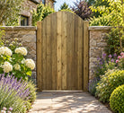Curved top tongue and groove garden gate front in landscaped garden